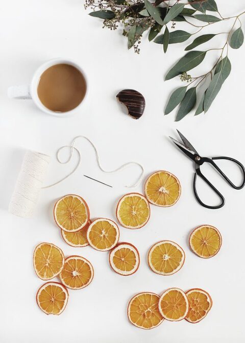 dried oranges on white table with scissors, coffee and string