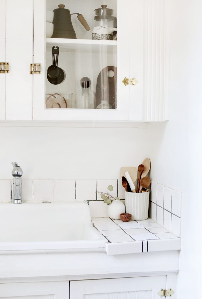 white kitchen cupboards and sink with natural wood accents