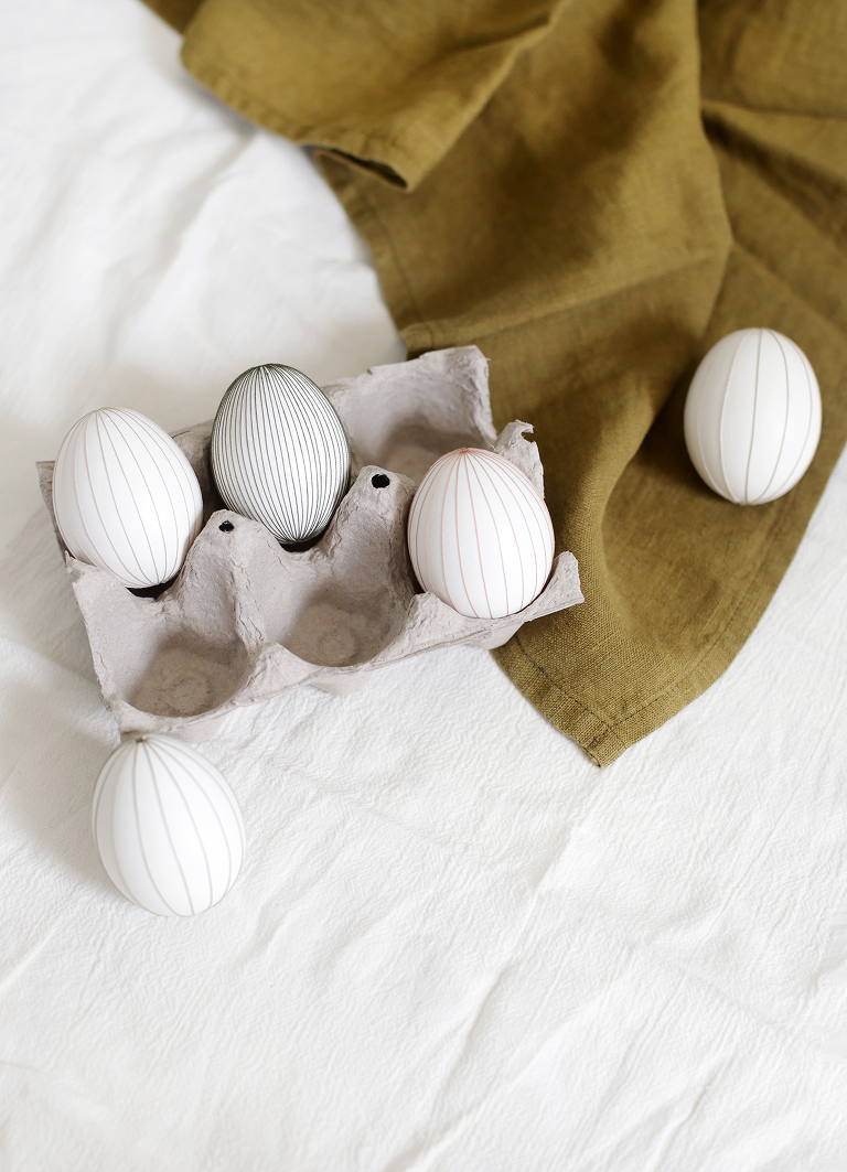 cardboard egg carton with three string eggs in it and two laying beside it