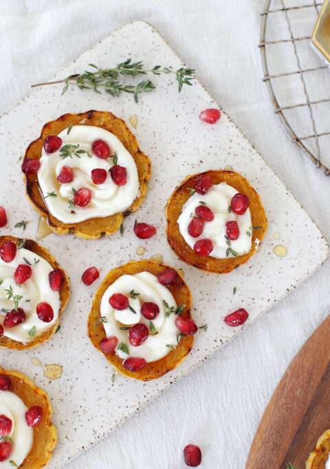 squash rings with cheese, pomegranates and thyme on ceramic platter