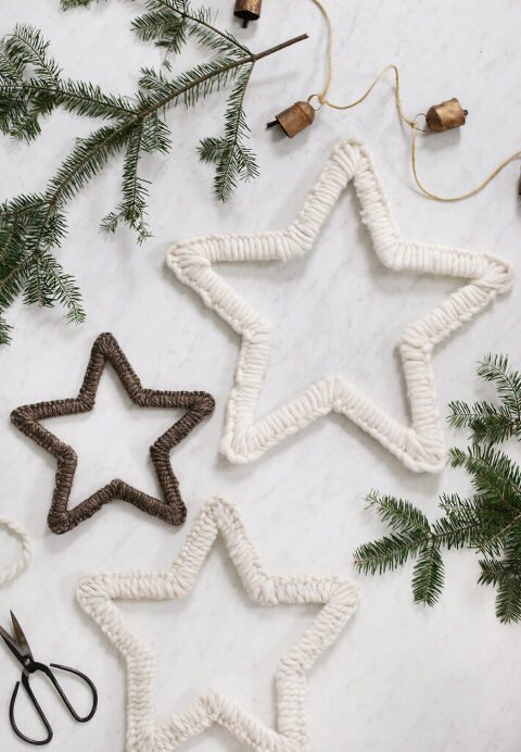 three yarn stars laid out on white marble with pine branches virtually them