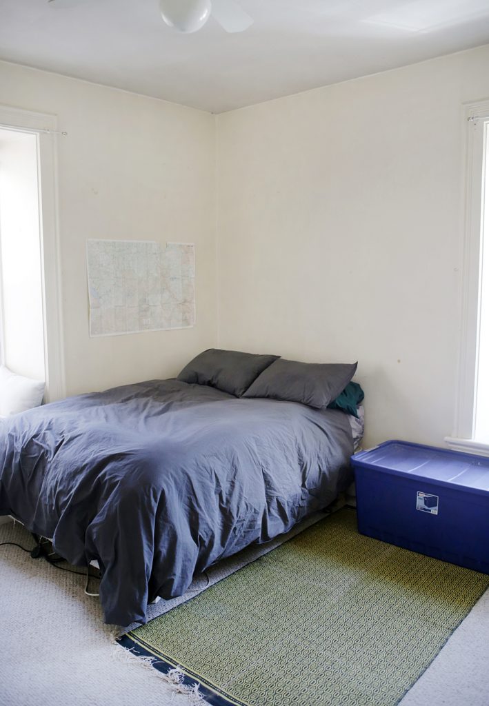 grey bed next to blue plastic tote