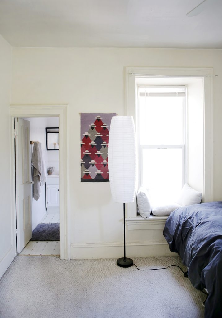 open room with lamp and woven wall hanging