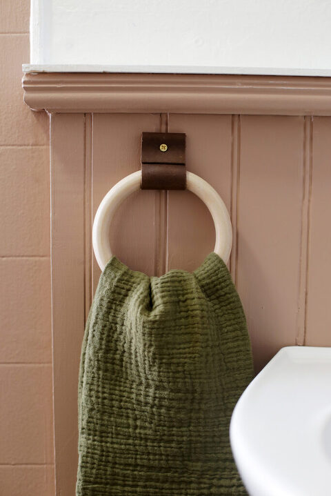 close up of olive green hand towel hanging on brown pink wall