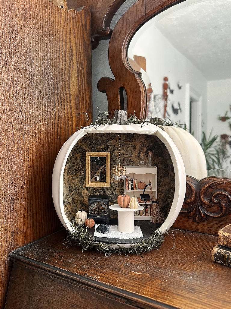 dollhouse pumpkin on wooden shelf with halloween miniature decor inside