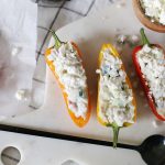 three mini peppers cut in half and stuffed with chicken salad on marble cutting board