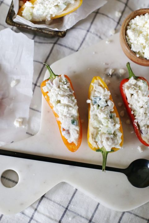 three mini peppers cut in half and stuffed with yellow salad on marble wearing board