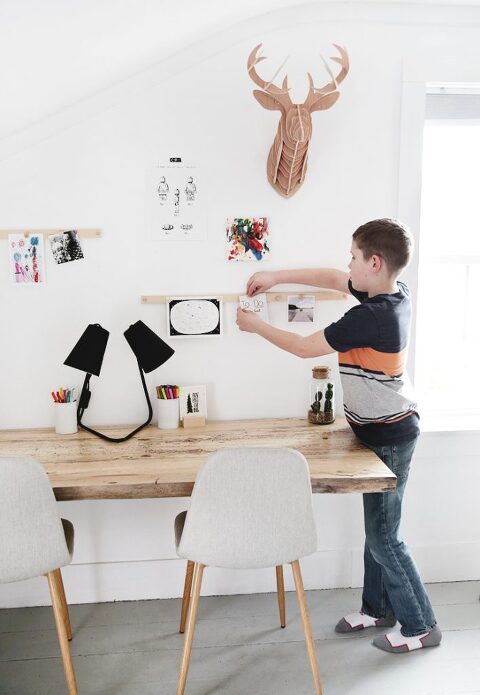 child in bedroom hanging paper above wood desk on a display rail