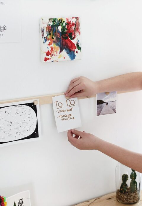 wood magnetic display rail with child's hands hanging a to-do list on the rail