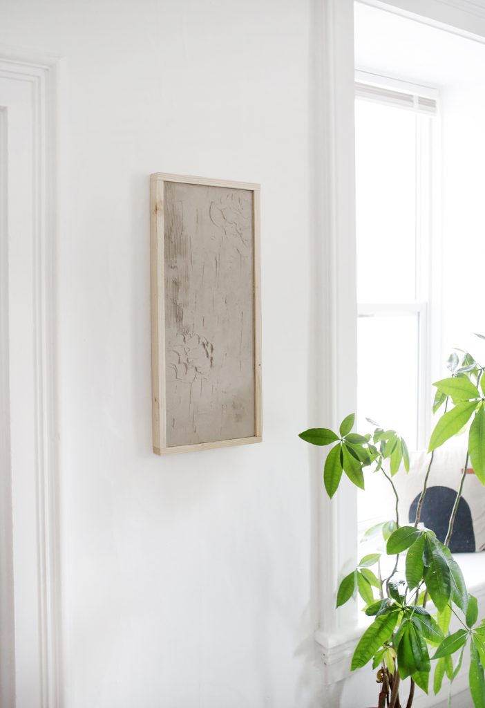 plaster wall art on white wall next to plant