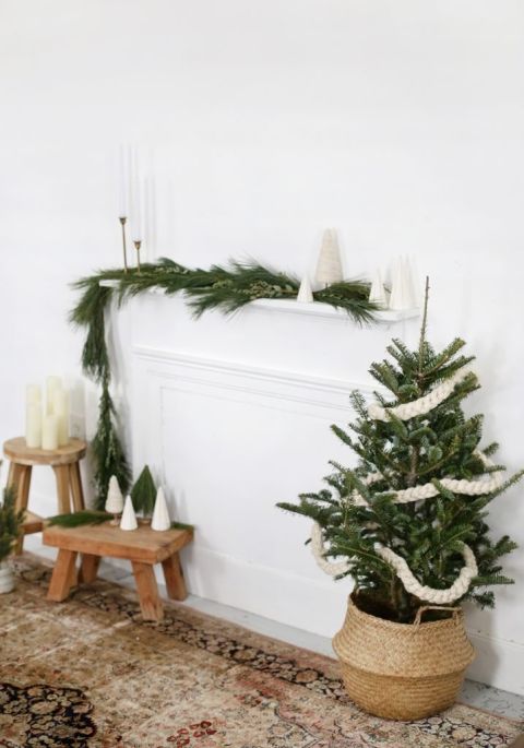 yarn garland on mini christmas tree in front of white fireplace