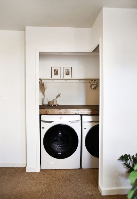 white room with laundry closet with white and taupe walls with wood counter