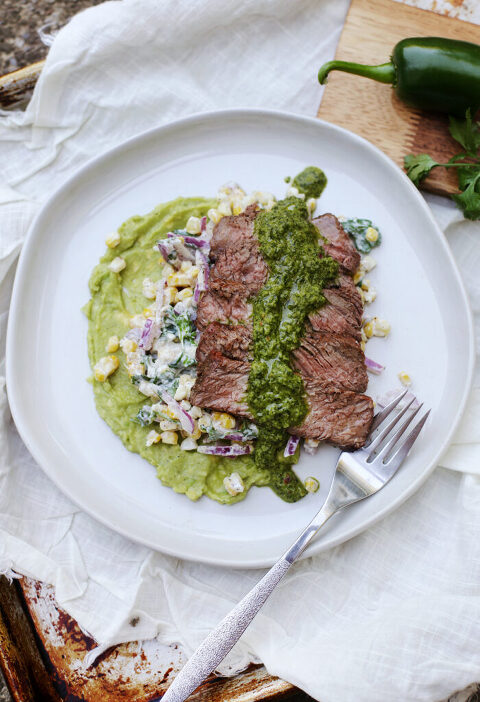 overhead shot of steak and chimichurri dinner on white plate set on tray with linty white linen
