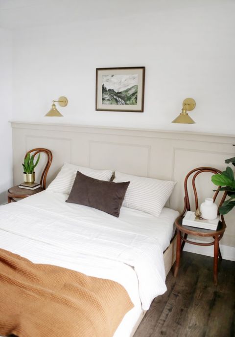 bedroom with taupe half wall and neutral decor pieces and chair nightstands