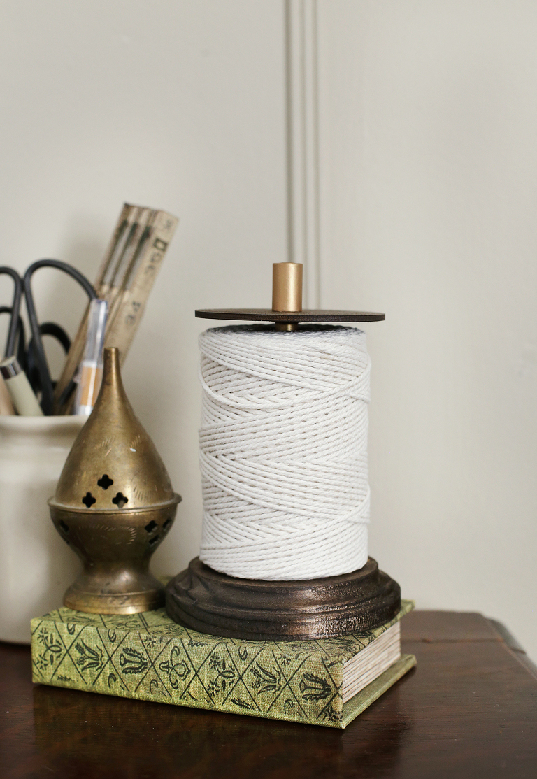 twine on dark wood holder sitting on garden book next to brass incense holder