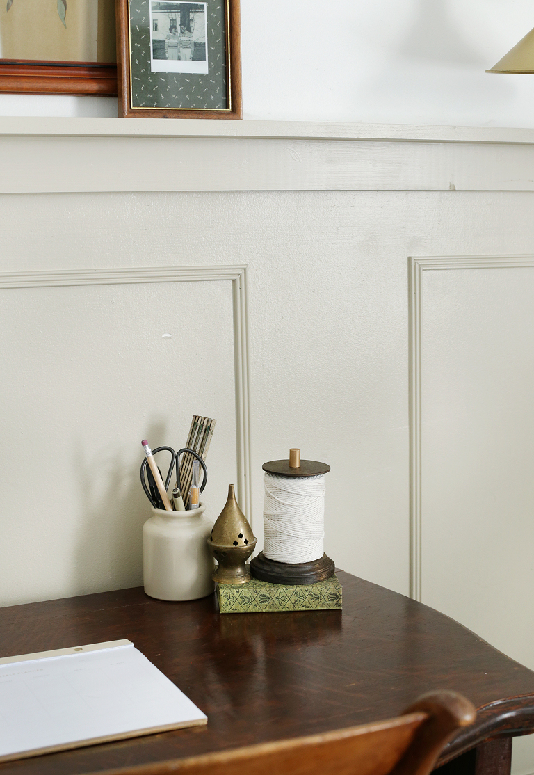 desk scene with jars of writing utensils and scissors with string on green book next to incense holder