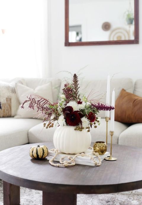 pumpkin vase with florals next to candles and mini pumpkin