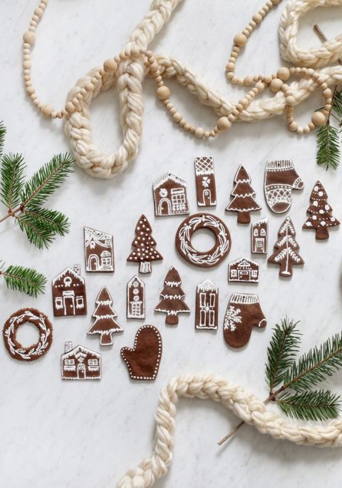 large group of gingerbread salt dough ornaments laying on white background surrounded by pine and garlands