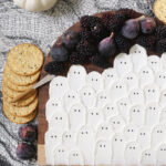 goat cheese board with fruit and crackers on black webbing