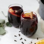 two glasses of mulled wine with oranges and cinnamon sticks