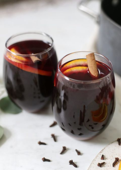 close up of two glasses of mulled wine with fruit and cinnamon garnish