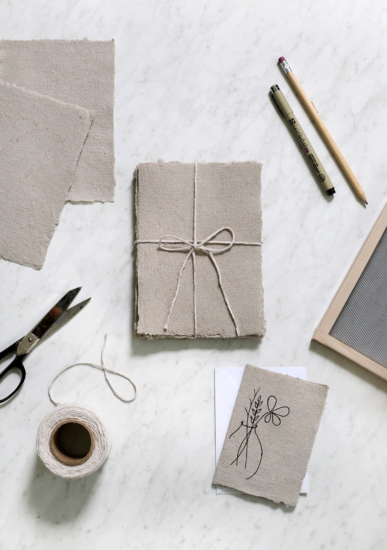 overhead shot of recycled paper from egg cartons surrounded my mould and deckle, scissors, writing utensils, and string