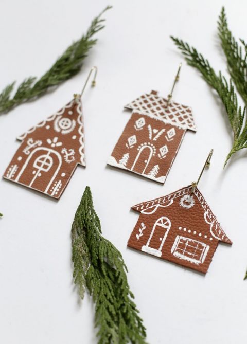 three gingerbread house ornaments next to greenery