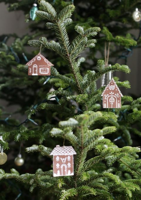 three gingerbread house ornaments hanging on a Christmas tree