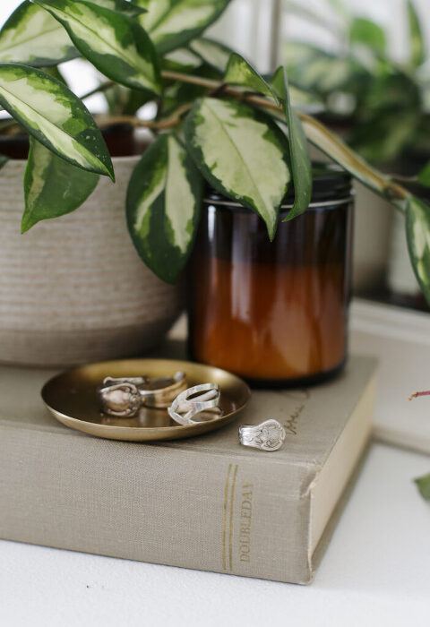 rings on contumely tray on top of typesetting next to umber candle and plant