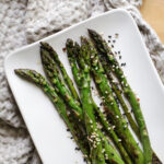 roasted asparagus tips on a white platter on a kitchen towel