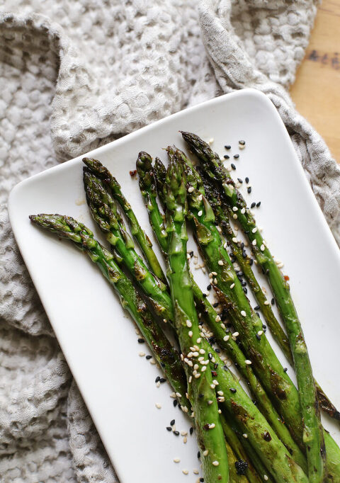 roasted asparagus tips on a white platter on a kitchen towel