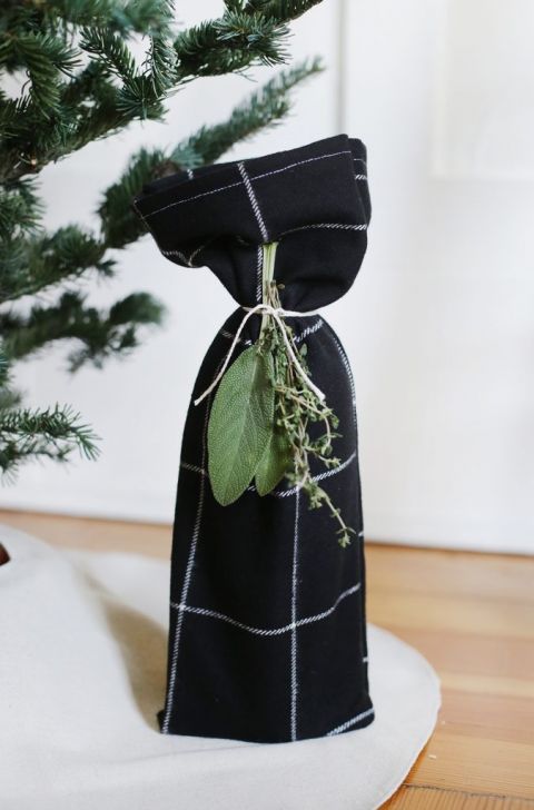 wine bottle in black fabric bag with herbs tied to it