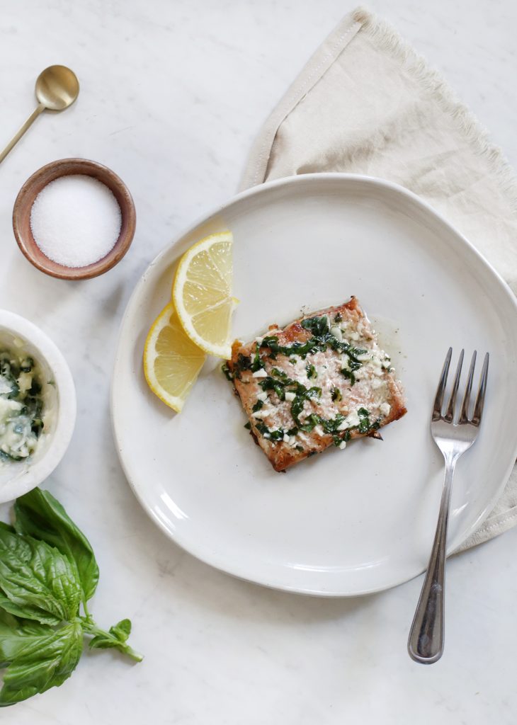salmon on plate with lemons surrounded by napkin, basil, salt