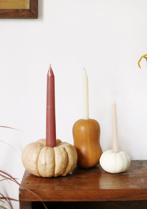 three mini pumpkins with taper candles in them grouped together