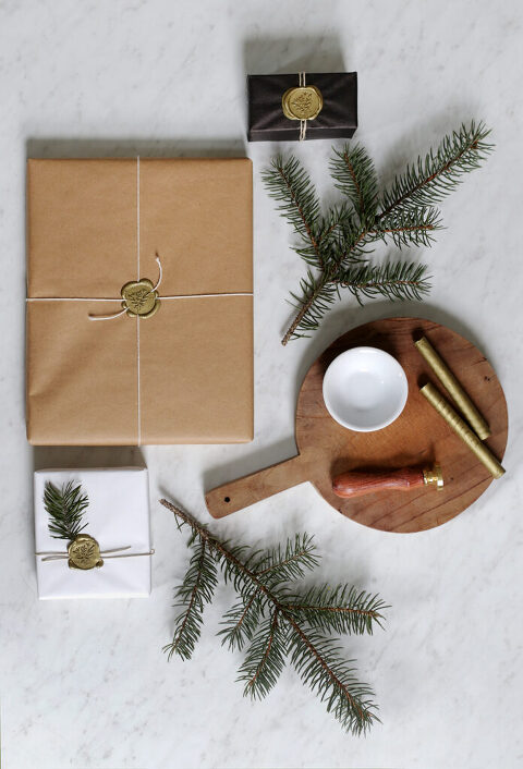 wax stamping kit on cutting board next to pieces of pine and simple wrapped presents