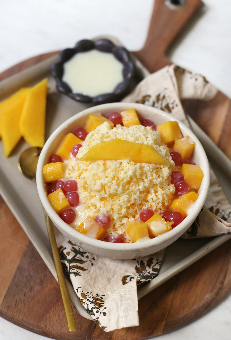 shaved mango bingsu in white bowl with fresh mango and boba on top