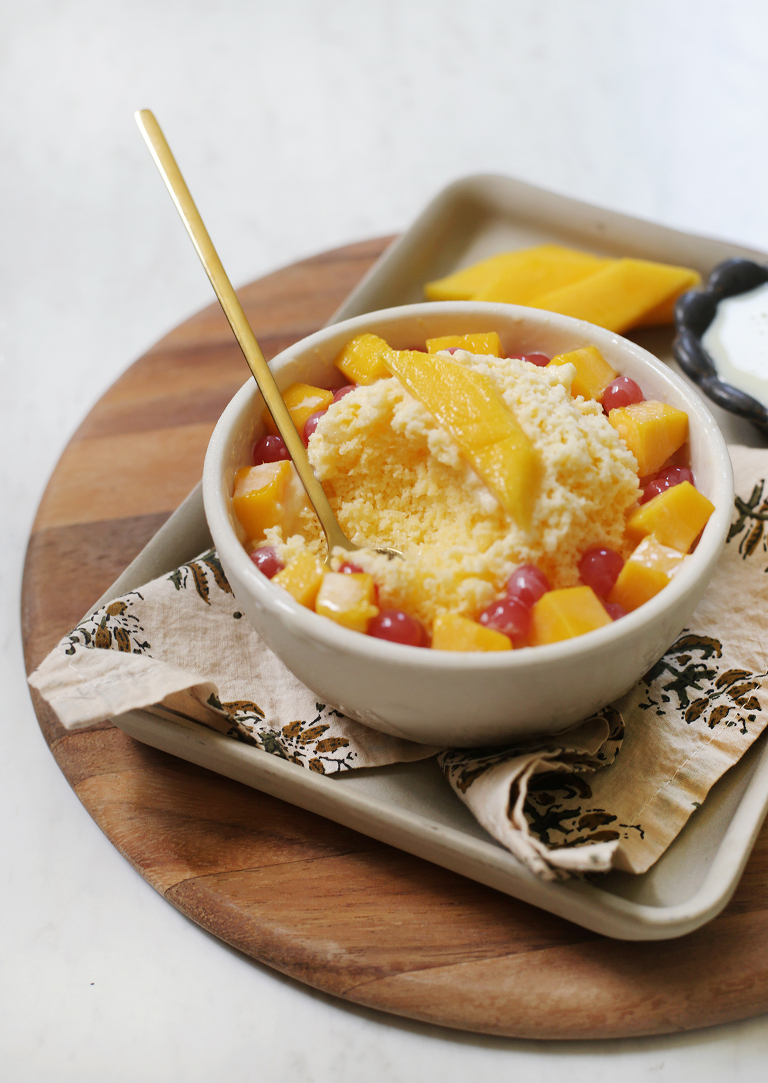 gold spoon in a bowl of mango bingsu with fresh mango and boba toppings