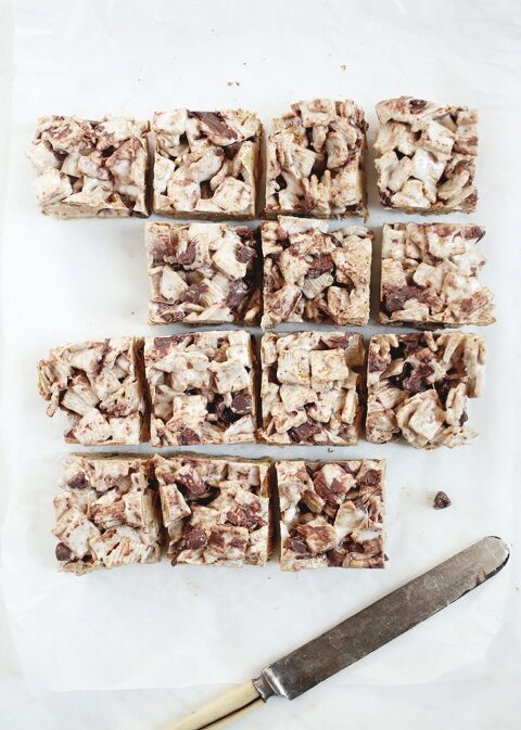 golden graham s'mores bars on parchment paper, cut into squares with antique knife sitting next to them