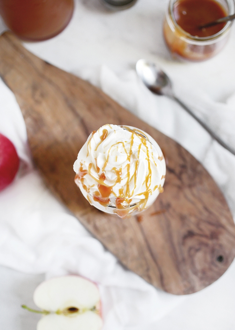 cutting boards with glass cup on with whipped cream and caramel drizzle 