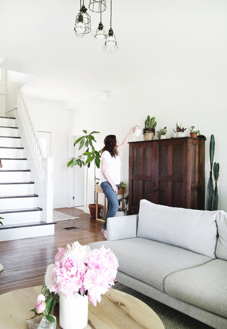 woman watering plants in living room