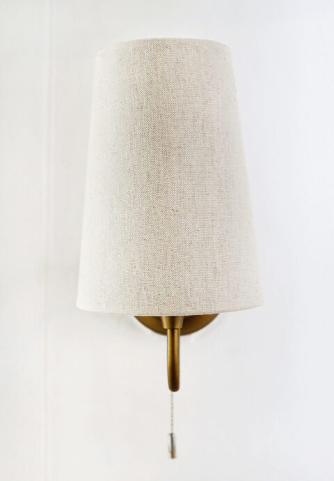 close up of creamy linen lampshade on gold wall sconce