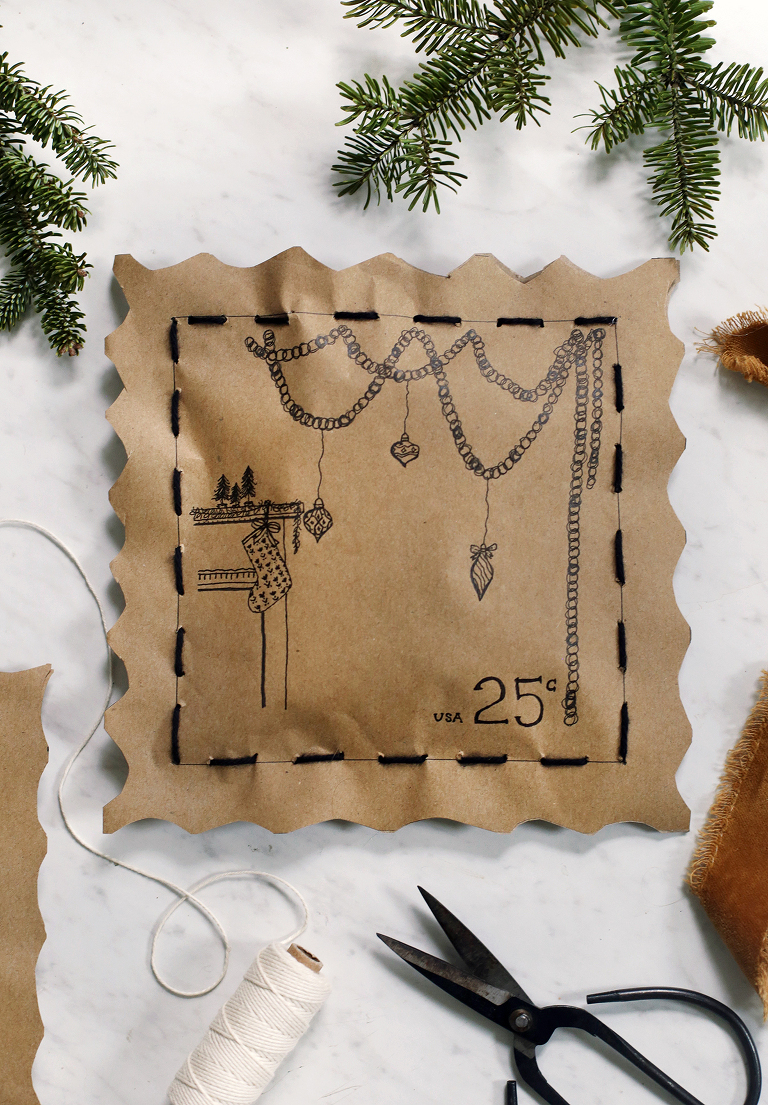 hand drawn mantle and garland on hand stitched christmas gift wrapping next to yarn and ribbon