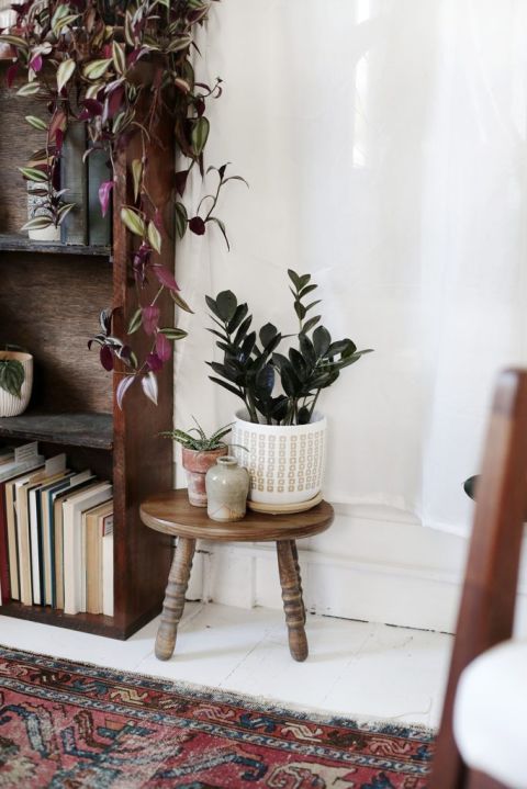 small stool next to a wooden shelf with plants on top in ceramic planters