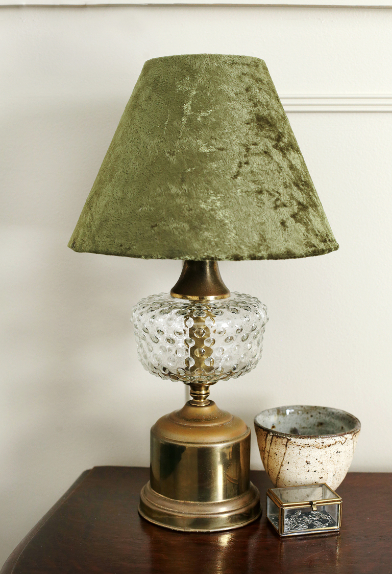 vintage lamp with velvet shade next to ceramic dish and glass box on desk