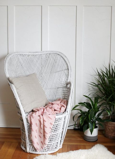 pink muslin blanket on white chair next to plants