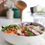 peanut sauce being drizzled over salad