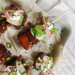 skewer through piece of pork belly, ribboned cucumber, with pickled veggies and wasabi mayo