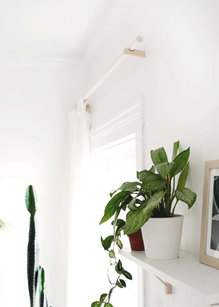 white wall shelves with plants and wood dowel curtain rod 