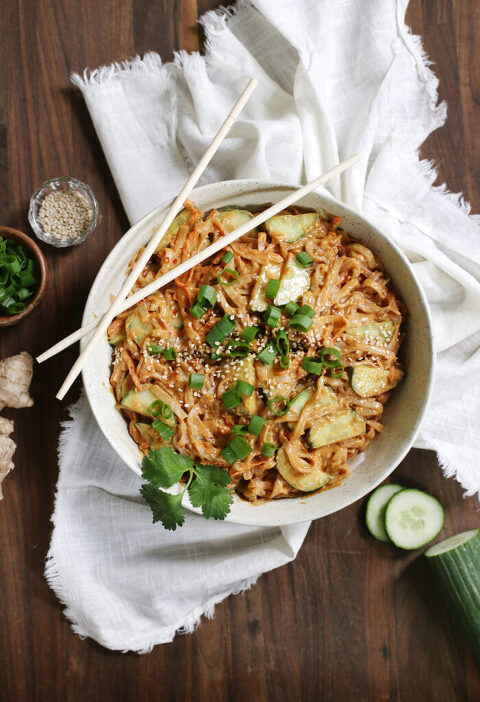 overhead shot of a trencher of peanut noodles over linen towel with ingredients spread around