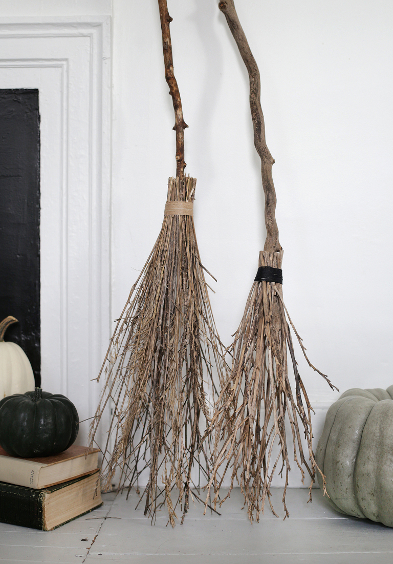 close up of handmade witches brooms against white wall